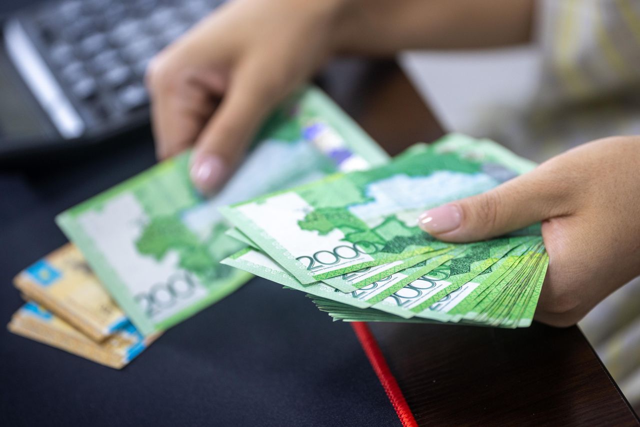 services-01 Person counting stacks of Uzbekistani som banknotes, showcasing financial transactions.