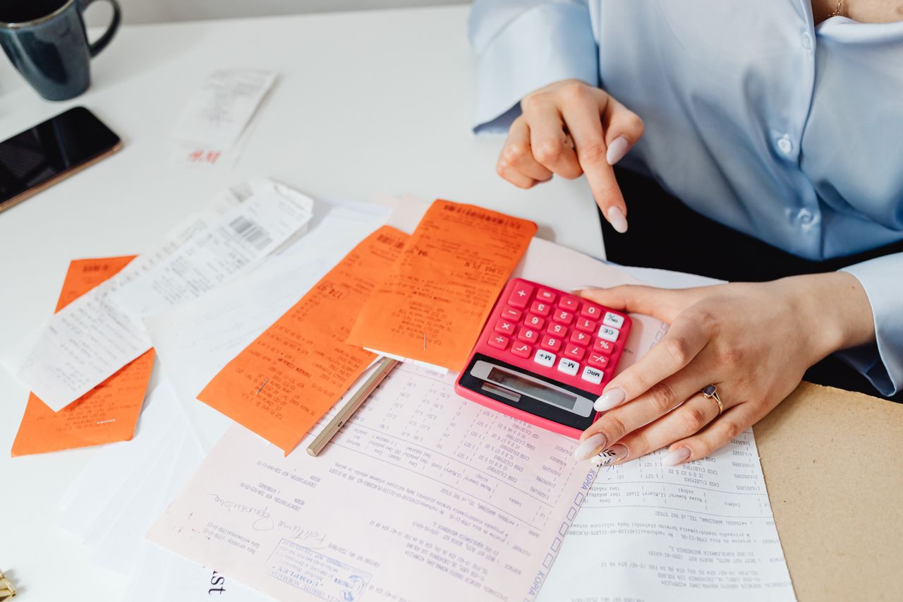 hero-img-02 Businesswoman calculates expenses using receipts and calculator at desk. Ideal for finance, accounting themes.